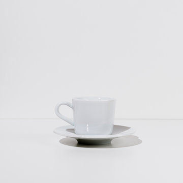 White cup and saucer on a table, selective focus, square image
