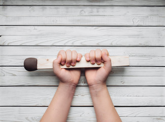 A big match in the hands of a girl on a wooden white background. Concept and photography. Creativity and copy space. Slight inflammation. Human choice.