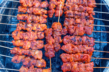 Thai street vendor sells grilled chicken meat at street food market in island Koh Phangan, Thailand. Closeup