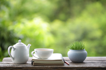 tea cup with small plant pot and diary notebook on wooden table