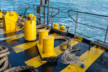 The deck of the ferry boat along with the a thick mooring rope and blue sea water wave, Thailand. Close up