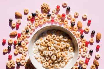 wholegrain flakes with berries and milk on pink. Healthy tasty breakfast cornflakes with blueberries, raspberries and red currant.Multigrain wholewheat healthy cereals with fresh berry.