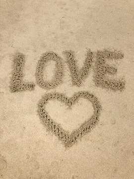 inscription love with a painted heart on the sand by the ocean