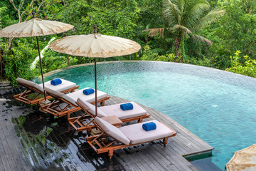 View of the swimming pool water and sunbeds in the tropical jungle near Ubud, Bali, Indonesia , top...