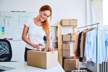 Young small business owner packing deliveries in modern office and storage space