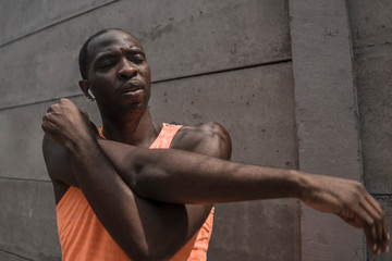 young attractive and athletic black African American man stretching arms and upper torso ready for running workout looking focused badass style in urban background
