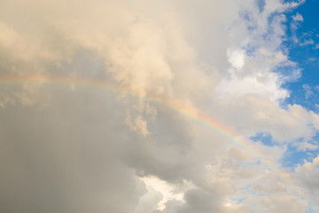 Fototapeta na wymiar Bright colored rainbow amid blue skies after rain on warm summer day