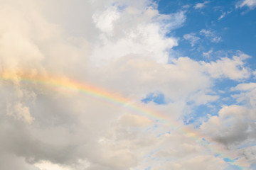 Fototapeta na wymiar Bright colored rainbow amid blue skies after rain on warm summer day