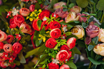 Bouquets of artificial flowers are sold at the fair. Corollas of colored small flowers. Closeup of national decorations and accessories for clothing.