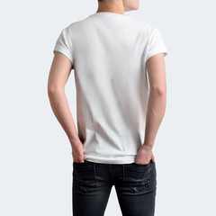 Pretty young man in blank white t-shirt and dark jeans with hands in pockets on a white blank studio background.