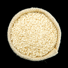 White sesame in a bag isolated on a black background. View from above. Seasoning on isolate. Dry spices.