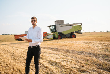 Happy farmer in the field checking corn plants during a sunny summer day, agriculture and food production concept