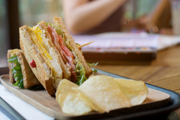 Club sandwich with bacon - chicken, fie egg, cheese, potato and lettuce on wooden tabel in cafe...