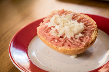 Teller  Mettbrötchen mit Mett und Zwiebeln auf Holz Tisch