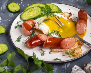 Breakfast of scrambled eggs with sausages, fresh cucumbers and fresh parsley during the meal