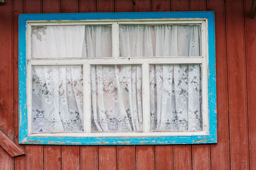 Old rustic window in blue and white on a brown wall