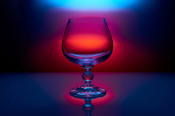 empty cognac glass on color reg blue lighting background