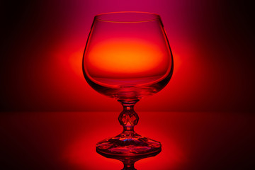 empty wine glass on color red lighting background