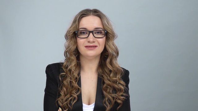 Bussines woman stands worrying in expectation at grey background, slow motion