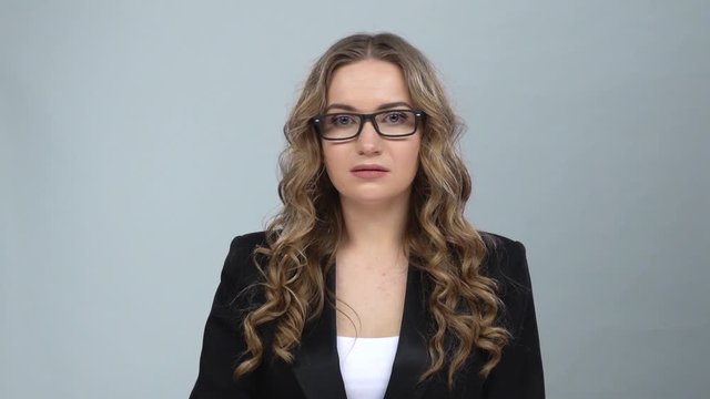 Bussines girl in glasses looks in surprise at camera and is shocked by what she saw, slow motion