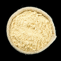 Ginger powder in a bag isolated on black background. View from above. Seasoning on isolate. Dry spices.