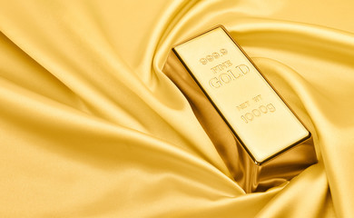Gold bar on satin fabric. financial concept.