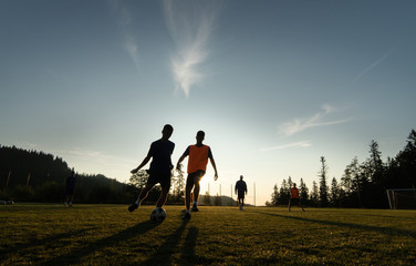 Boys playing soccer at sunset