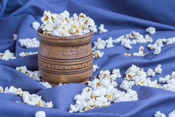 Popcorn in a wooden mug on a blue background.