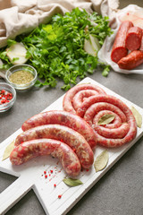 Board with fresh raw sausages and spices on table