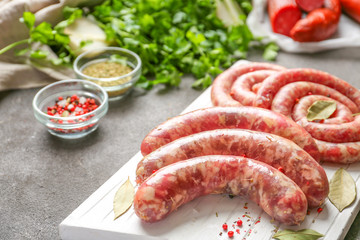 Board with fresh raw sausages and spices on table