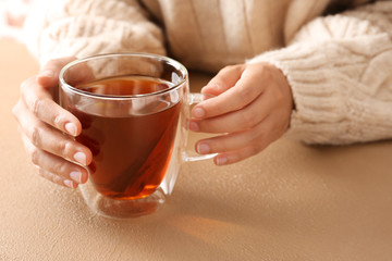 Woman with cup of hot tea sitting at table, closeup