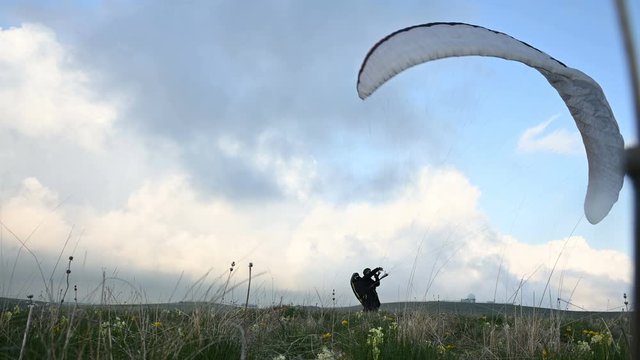 A male athlete paraglider raises a wing in an outdor against the backdrop of evening clouds but cannot fly. Failure while trying to take off