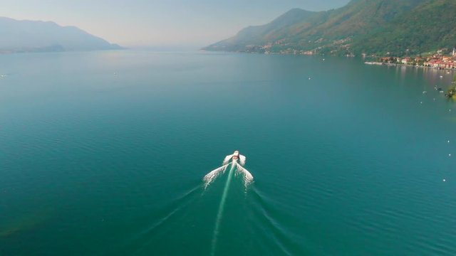 Aerial crane shot of a motorboat cruising on the Lake Maggiore on a bright sunny day.