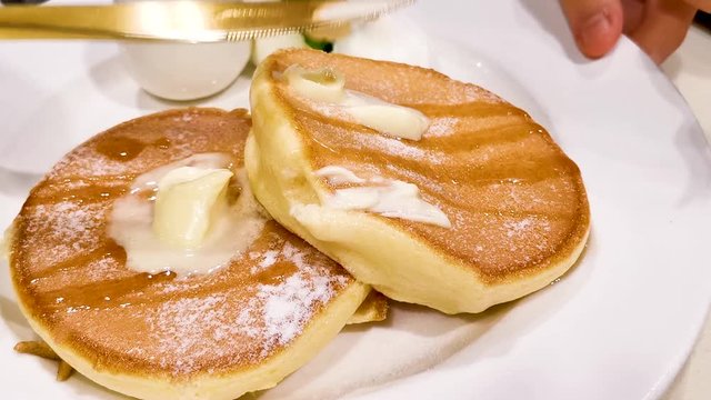 Paints butter on famous dessert Souffle pancake, Japanese style in Hong Kong cafe restaurant