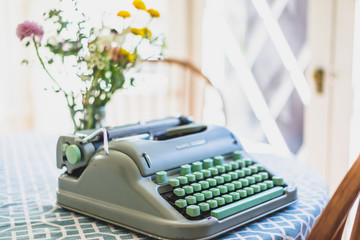 blue typewriter on table with flowers and natural light