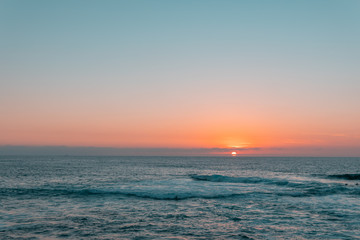 Sunset above sea or ocean. Wavy surface of water. Horizon line. Teal and orange colors concept