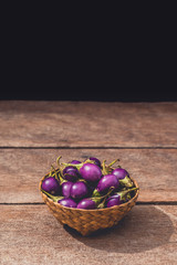 Fresh raw Purple Eggplant in wicker basket on wooden table