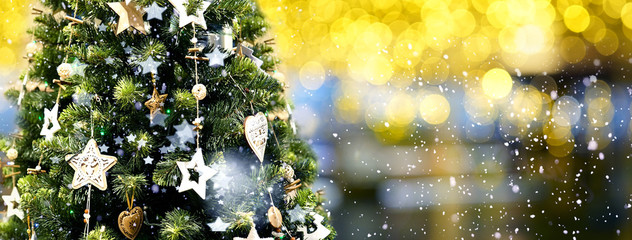 Christmas green tree decorated with wooden garlands of stars on a blurred, sparkling evening dark background with beautiful bokeh circles, copy space.