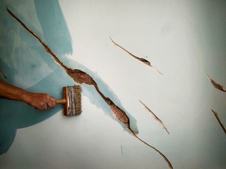 home repair, a man brushes the cracks in the wall before puttying