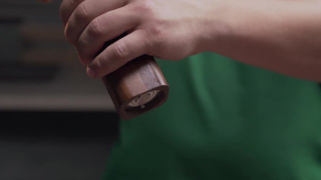 Macro shot: chef uses salt mill to add some salt for his meal, salt falls in slow motion, milling the salt, using kitchen stuff, Full HD prores 422 HQ