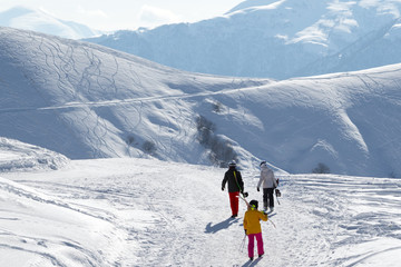 Fototapeta na wymiar Skiers and snowboarders walk on snowy road at sunny winter morning