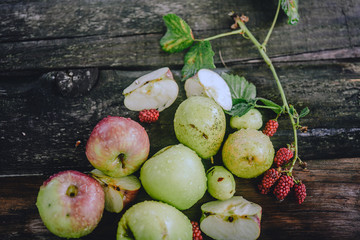 Explosion of different berries. Photo of apples, plums, blackberry, on wooden table. Top view. High resolution product.