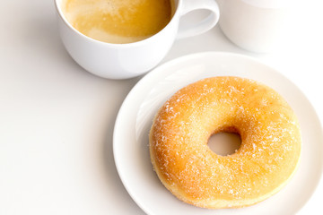 Cup of coffee with classic sugar donut on white background.Copy space