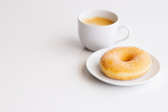 Cup of coffee with classic sugar donut on white background.Copy space