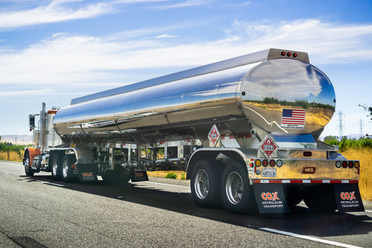 June 28, 2019 Tracy / CA / USA - Tanker truck driving on the freeway, the road and sky reflected in its shiny cistern;