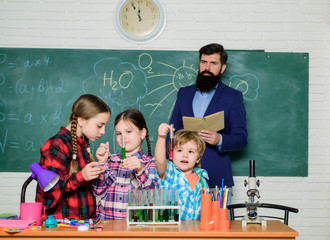 happy children & teacher. back to school. kids in lab coat learning chemistry in school laboratory. doing experiments with liquids in chemistry lab. chemistry lab. Confident pharmacist