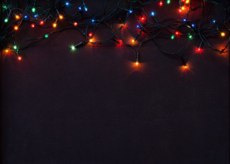 Fototapeta na wymiar Christmas garland with colorful lights on brown textile
