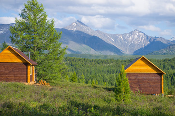 Fototapeta na wymiar House for rest in taiga against the background of the high mountains of Altai in Russia