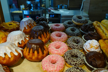 Cakes and doughnuts on the counter in the pastry shop where the chef is cooking.  