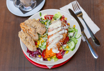 Dinner at restaurant. Close-up salad with grilled chicken, corn, tomato and cucumber